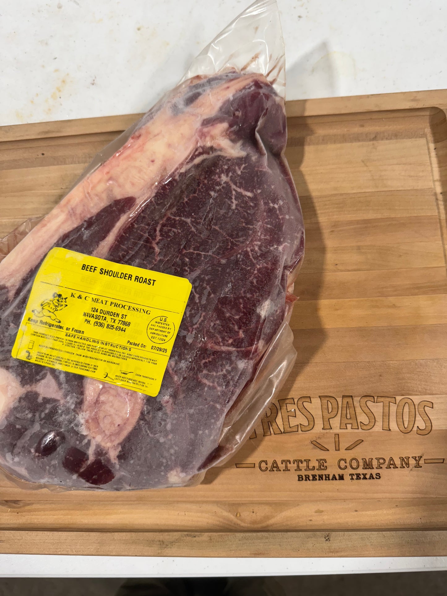 Beef shoulder roast with a label on a wooden cutting board, featuring 'Pres Pastos Cattle Company'.