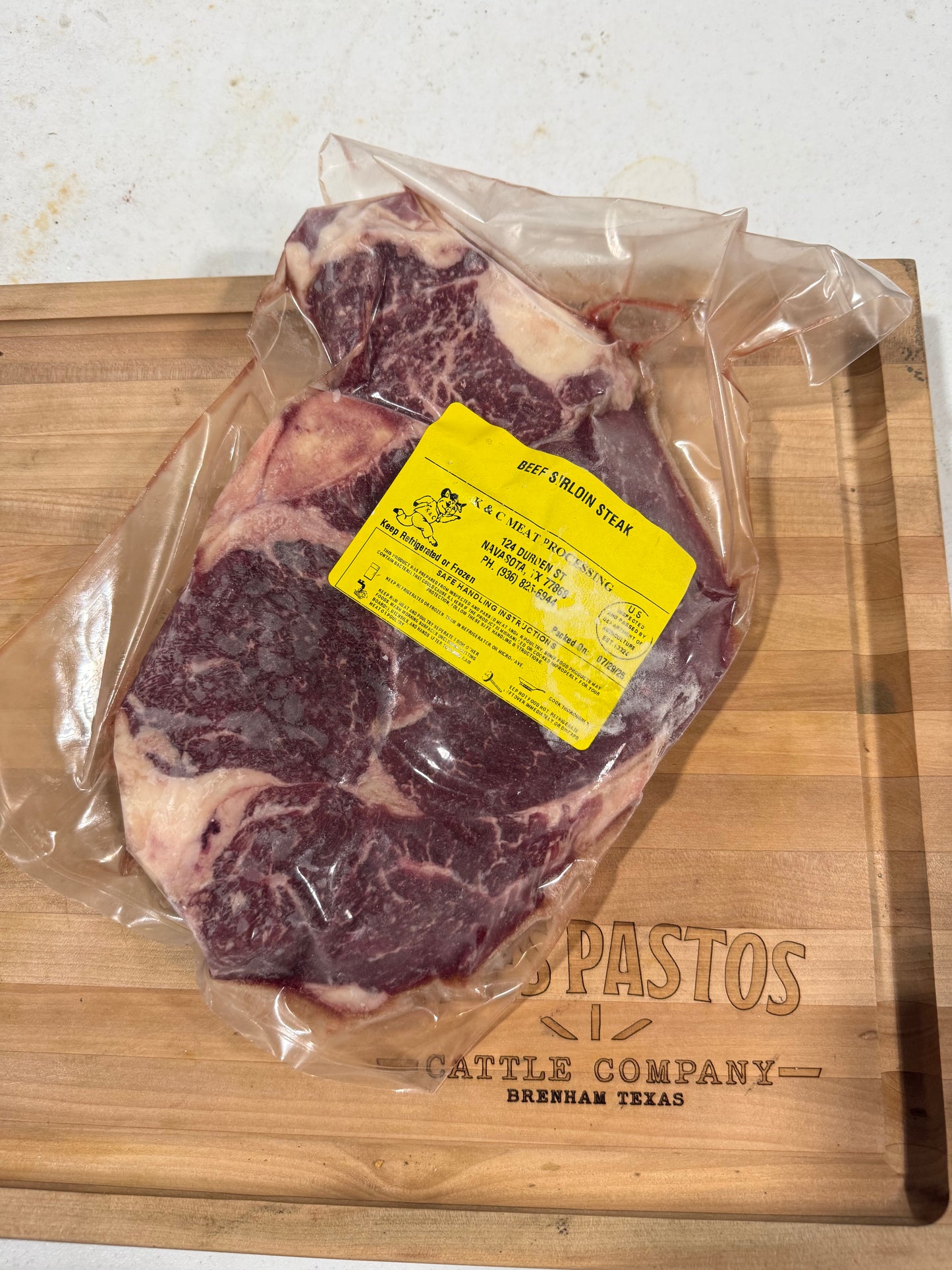 Packaged beef sirloin on a wooden cutting board with Tres Pastos Cattle Company branding.
